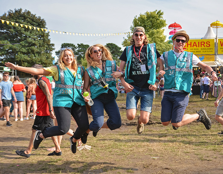 Jobs and Volunteering at Camp Bestival Dorset 2022 with Hotbox Events - Volunteers jumping in the village - 2022-001 740x580Px72Dpi