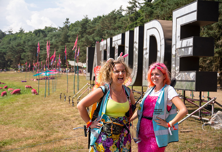 Volunteer at Latitude Festival 2022 with Hotbox Events - Pixie volunteers laughing in front of latitude sign 2022-001 740x506Px72Dpi