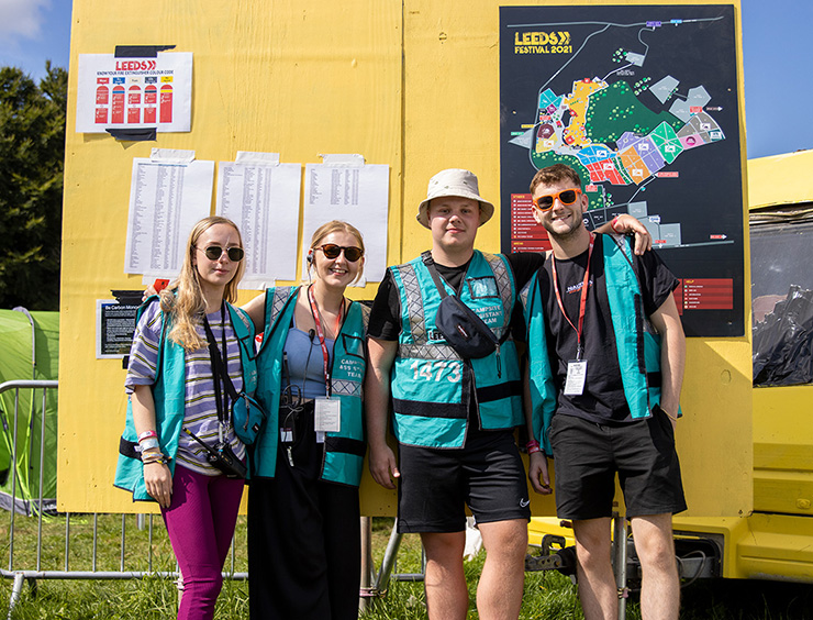 Volunteer at Leeds Festival 2022 with Hotbox Events - Volunteer group smiling with campsite sign 2022-001 740x564Px72Dpi