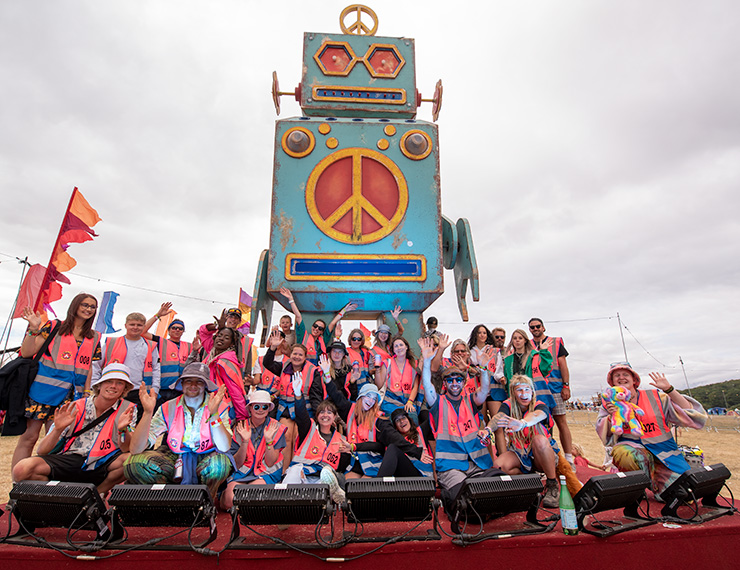 Jobs and Volunteering at Camp Bestival Dorset with Hotbox Events - Volunteer group in front of robot v2023001 740x570Px72Dpi